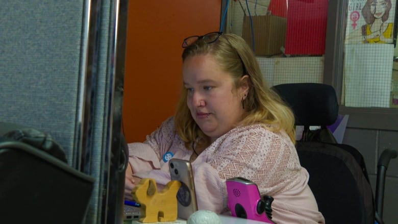 A 20-year-old woman in a wheelchair looks at a computer monitor